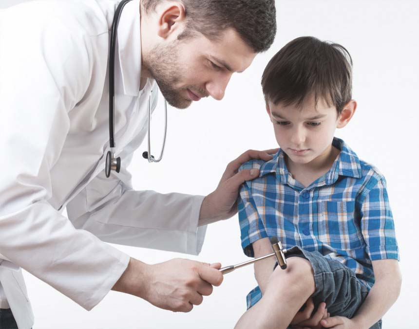 Doctor con bata blanca evaluando los reflejos musculares de un niño con un martillo de reflejos Trömner