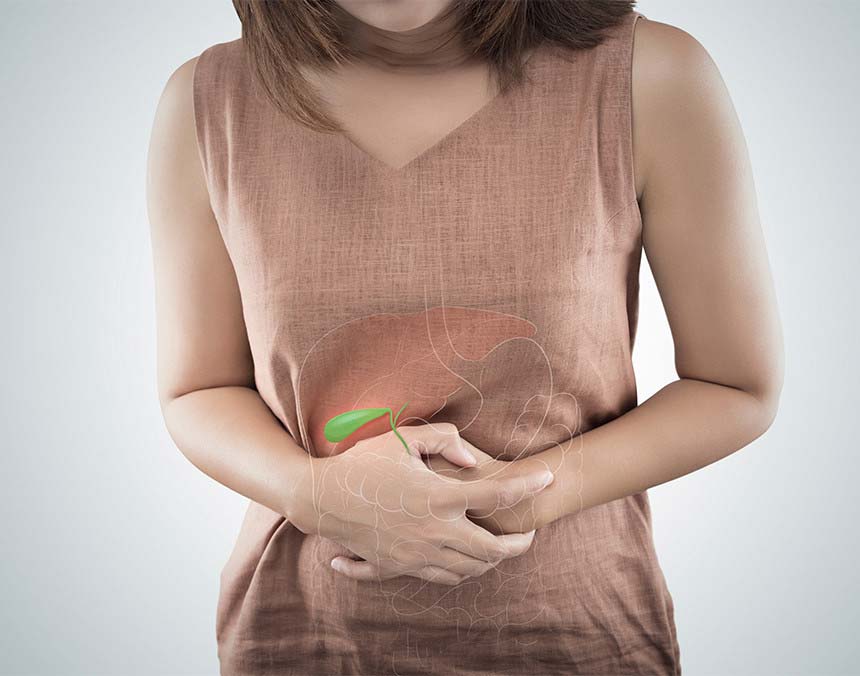 Mujer con blusa café agarrándose el abdomen, con un holograma del sistema digestivo, resaltando con color verde la vesícula