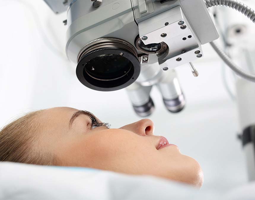 Mujer joven acostada sobre la camilla del equipo láser para realizarse una cirugía ocular