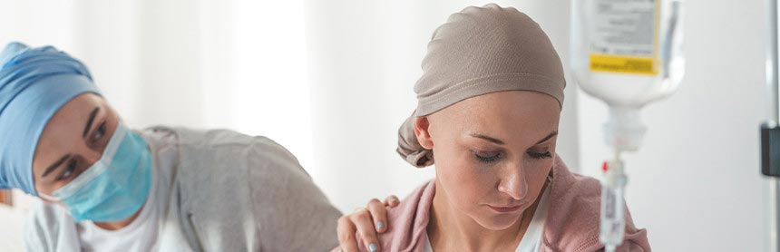 Paciente oncológico desanimada, mientras un familiar le toca el hombro derecho