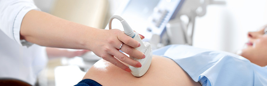 Mujer embarazada acostada en la camilla de un consultorio, mientras una ginecóloga le realiza un ultrasonido