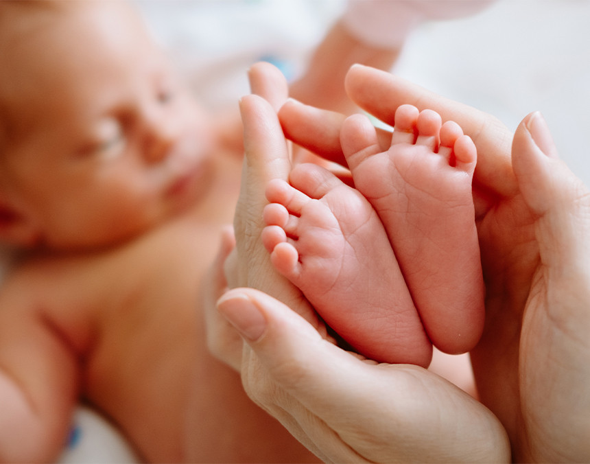 Manos de una mamá sosteniendo los pies de un bebé recién nacido