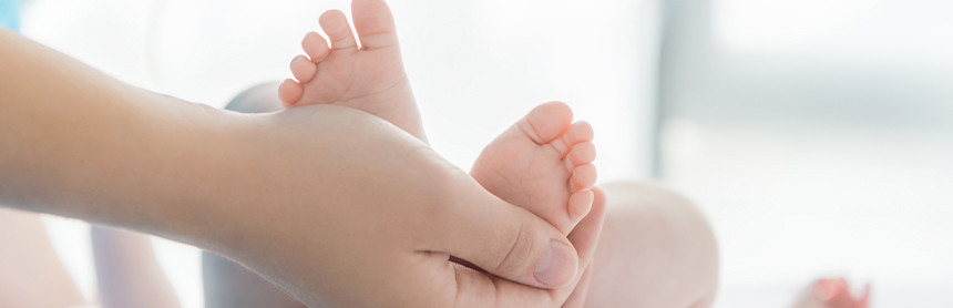 Mano de una mamá sosteniendo los pies de un bebé recién nacido