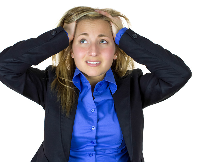 Mujer vestida con camisa azul y saco negro, agarrando su cabeza con las manos y teniendo un ataque de pánico
