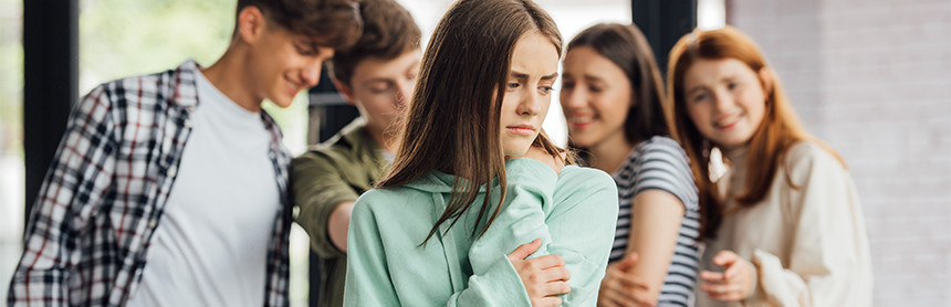 Una adolescente sintiéndose incómoda por las burlas de cuatro compañeros que están detrás de ella