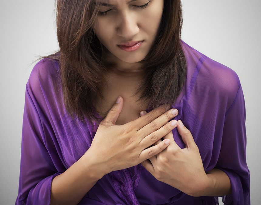 Mujer joven vestida con una blusa morada teniendo un ataque cardiaco