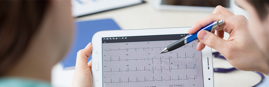 Cardiólogo analizando el electrocardiograma de un paciente en una tableta blanca