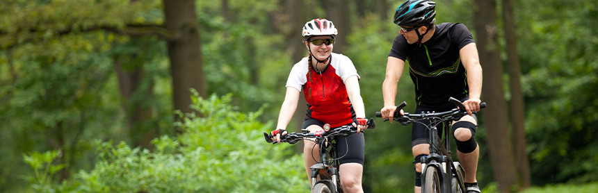 Dos jóvenes realizando ejercicio en bicicleta en un bosque