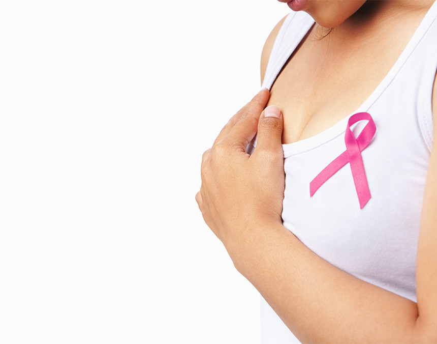 Mujer joven con una playera blanca y con la cinta distintiva de la lucha contra el cáncer de mama en su pecho