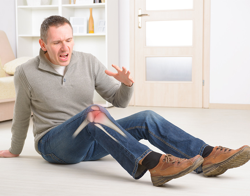 Hombre de mediana edad sentado en el suelo y sufriendo dolor de rodilla