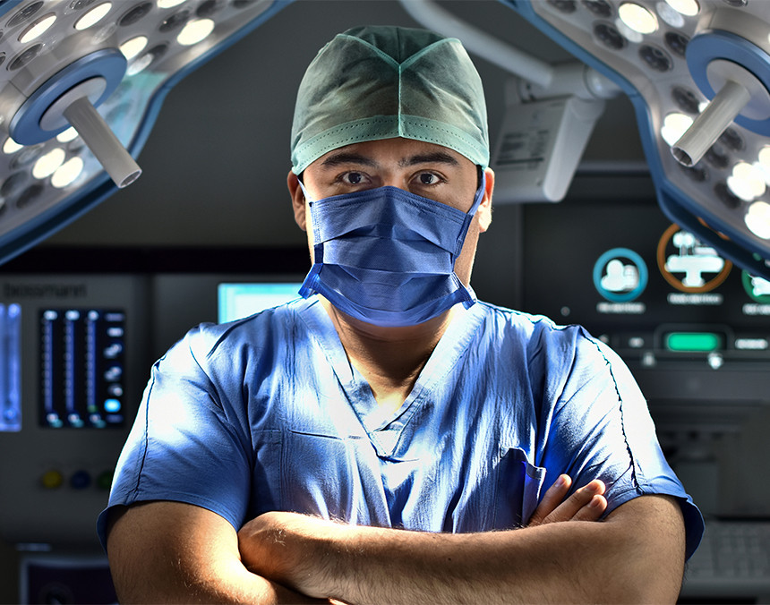 Médico con pijama azul para cirugía, gorro y cubrebocas, en un quirófano