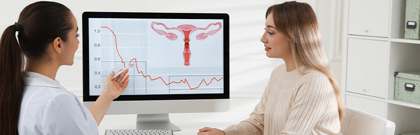 Mujer joven en consulta ginecológica. Observa la imagen de un útero en el monitor de una computadora