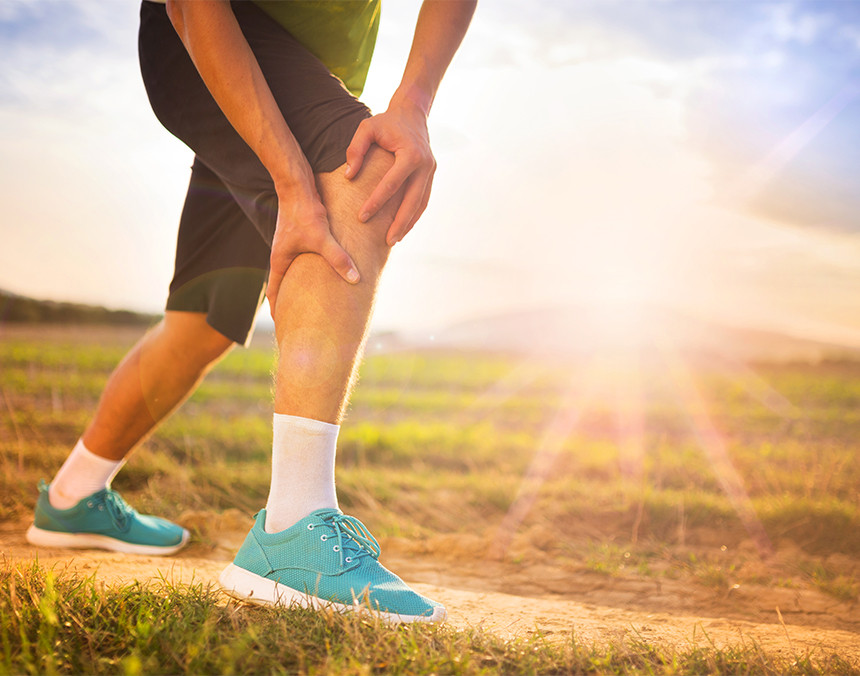 Joven corredor que está al aire libre presenta dolor en la rodilla derecha