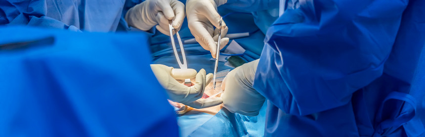 Tres médicos con pijamas azules para cirugía realizando un procedimiento quirúrgico