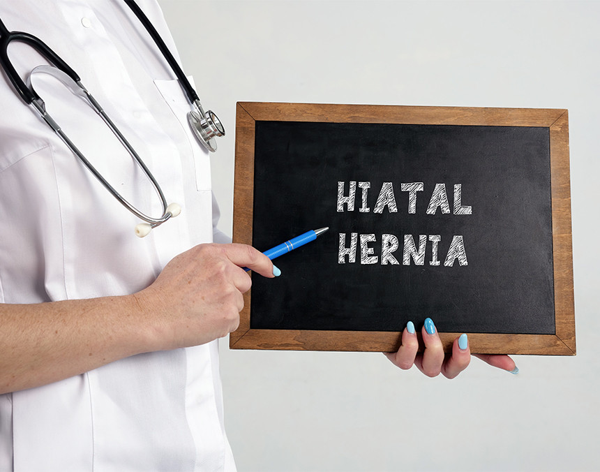 Doctora sosteniendo una pizarra de color negro y café con la palabra hernia hiatal
