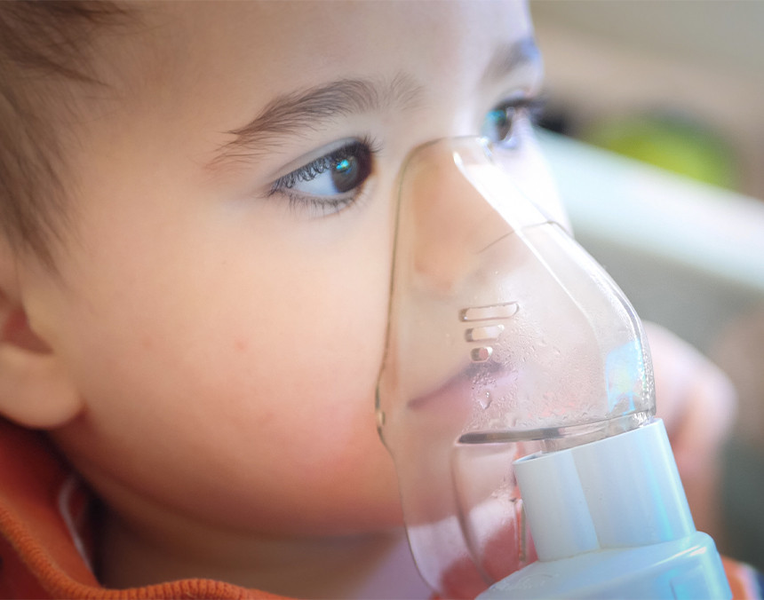 Niño pequeño con un inhalador en la nariz