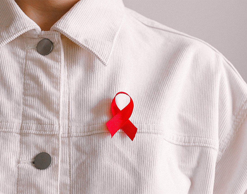 Hombre com camisa blanca y con una cinta roja relativa a la lucha contra el SIDA