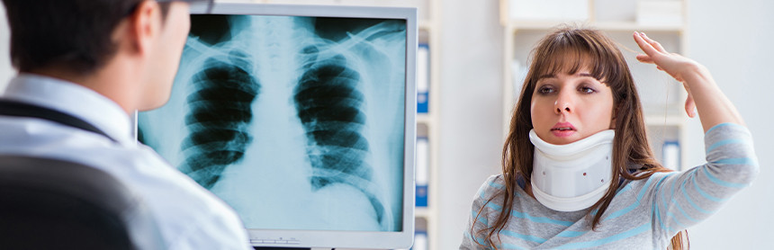 Médico sosteniendo una radiografía. Enfrente está una paciente que usa un collarín
