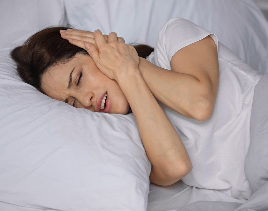 Mujer joven acostada en una cama sintiendo dolor en su oído izquierdo