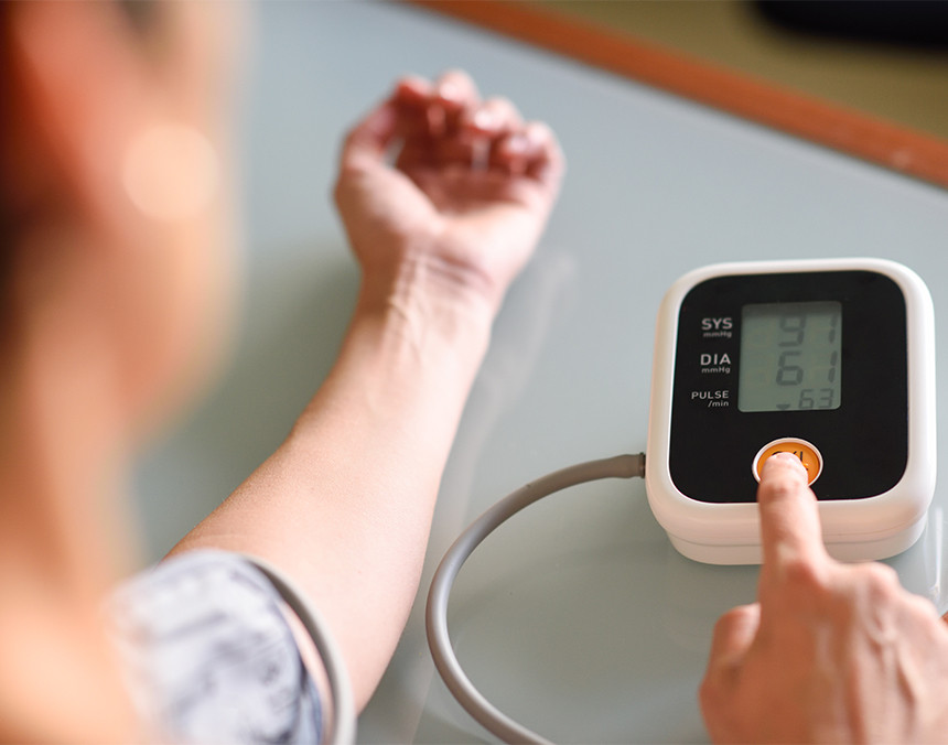 Mujer tomando su presión arterial con un baumanómetro blanco