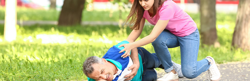 Mujer joven que está ayudando a un hombre que está sufriendo una convulsión en un parque