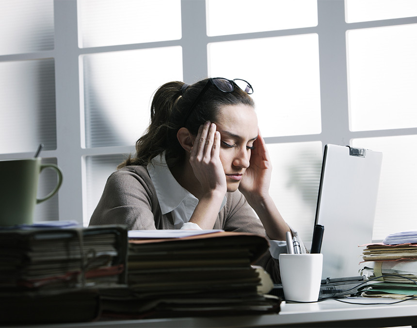 Mujer joven en una oficina sufriendo dolor de cabeza