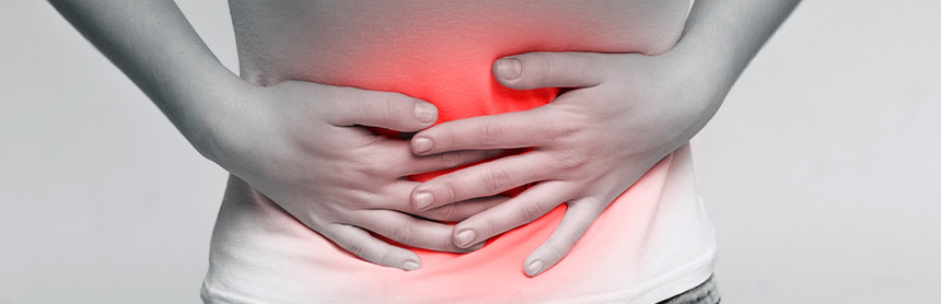 Mujer sufriendo dolor abdominal. La zona del abdomen está de color rojo