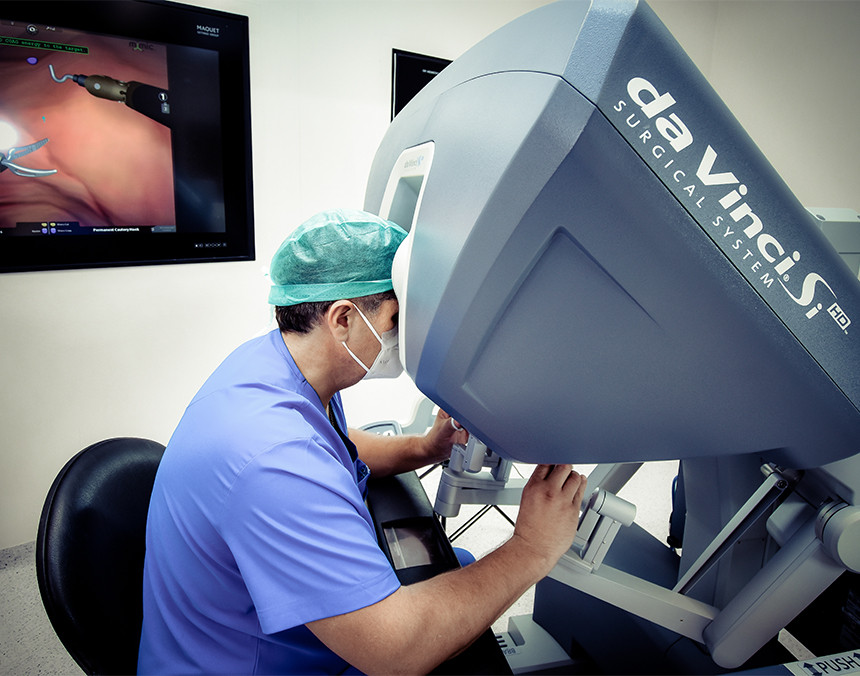 Médico con pijama para cirugía de color azul realizando un procedimiento quirúrgico con Robot Da Vinci SiHD