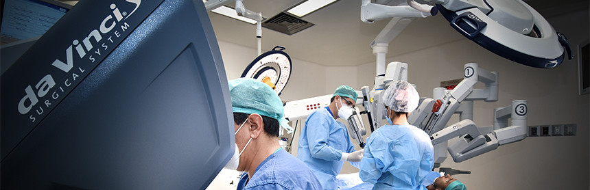 Médicos con pijama para cirugía de color azul realizando un procedimiento quirúrgico con Robot Da Vinci SiHD