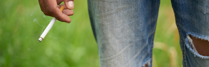 Vista parcial de la mano de un hombre sosteniendo un cigarro