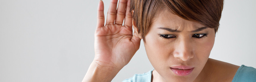 Mujer joven con cabello corta rojizo tiene problemas auditivos y está tratando de escuchar