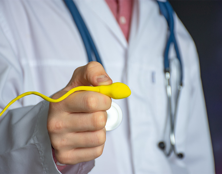 Doctor vestido con bata blanca sosteniendo un prototipo de un espermatozoide de color amarillo