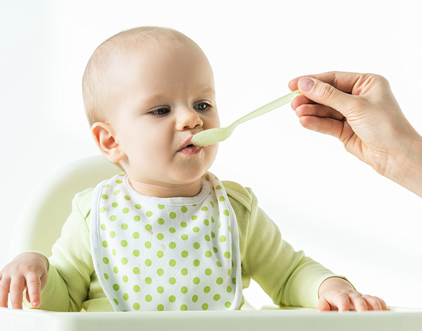 Madre alimentando a su bebé con una cuchara de plástico