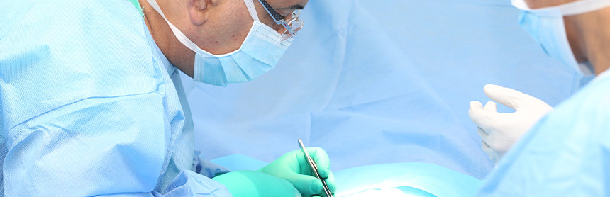 Dos médicos vestidos con pijama azul para cirugía realizando una cirugía de hernia
