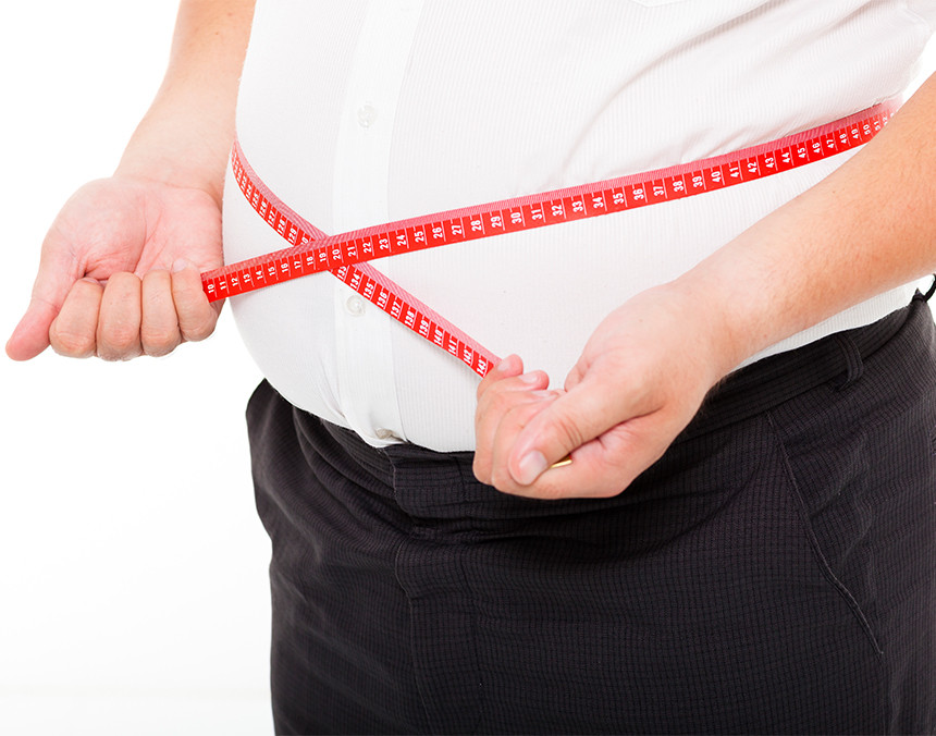 Hombre con obesidad midiendo su cintura con una cinta métrica de color rojo