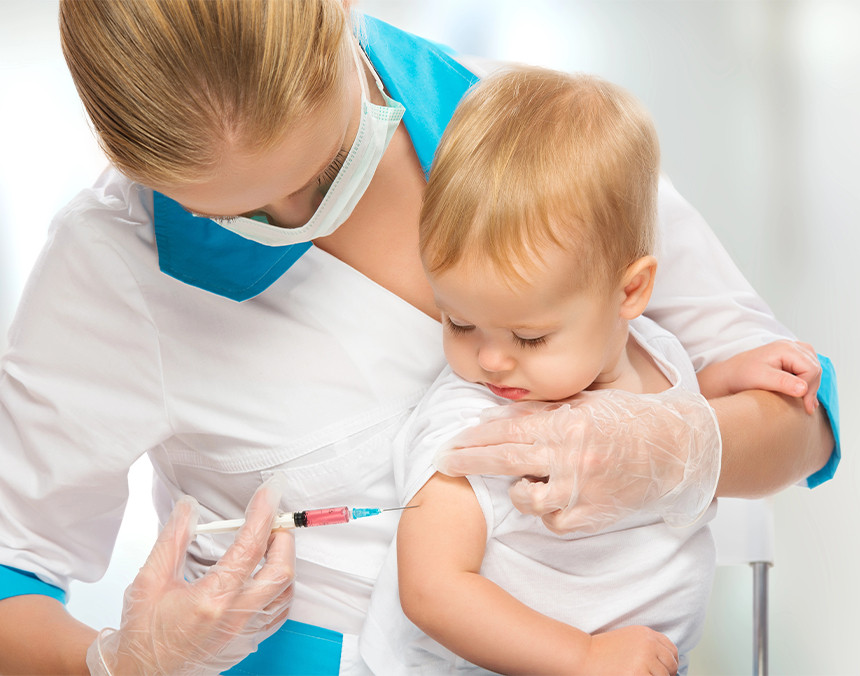 Doctora vestida con uniforme blanco vacunando a un bebé en el brazo derecho