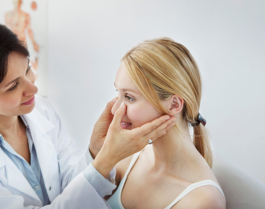 Doctora examinando el tabique de la nariz de una paciente en un consultorio médico