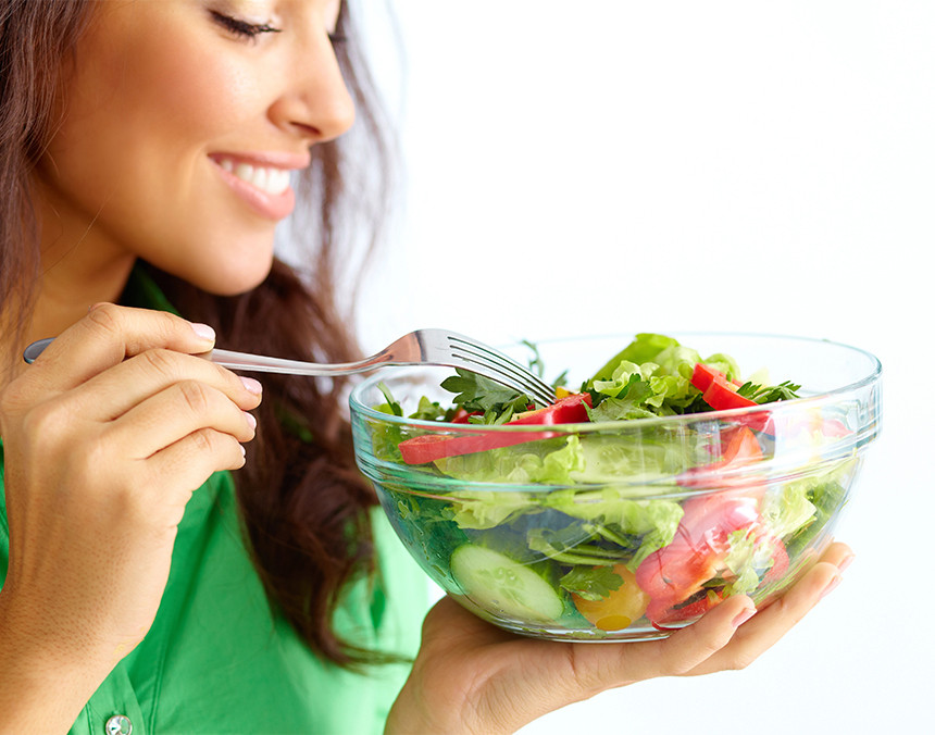 Primer plano de una mujer joven comiendo una ensalada de verduras frescas