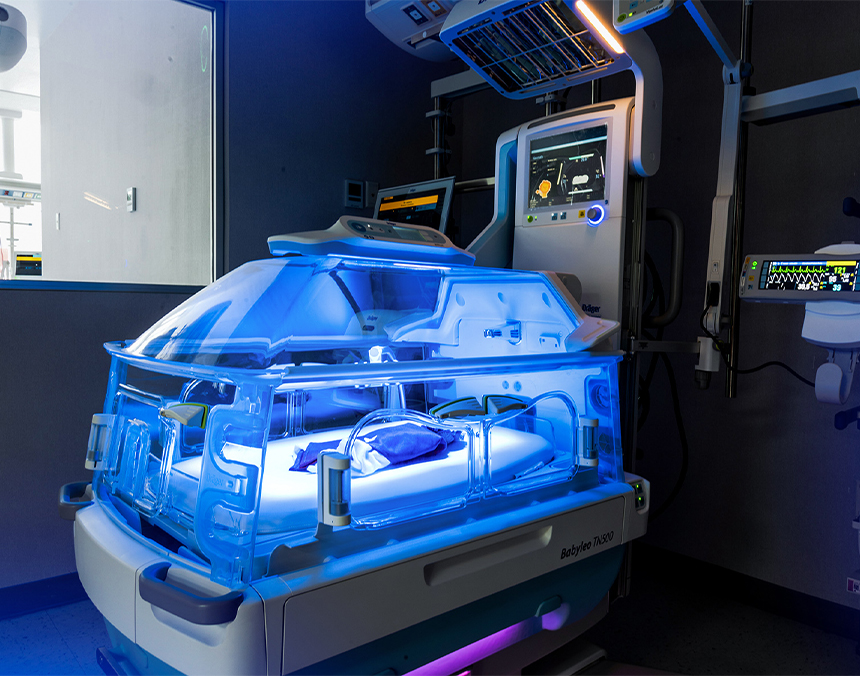 Incubadora y monitores de la Unidad de Cuidados Intensivos Neonatales en color azul y blanco, iluminados con una luz azul