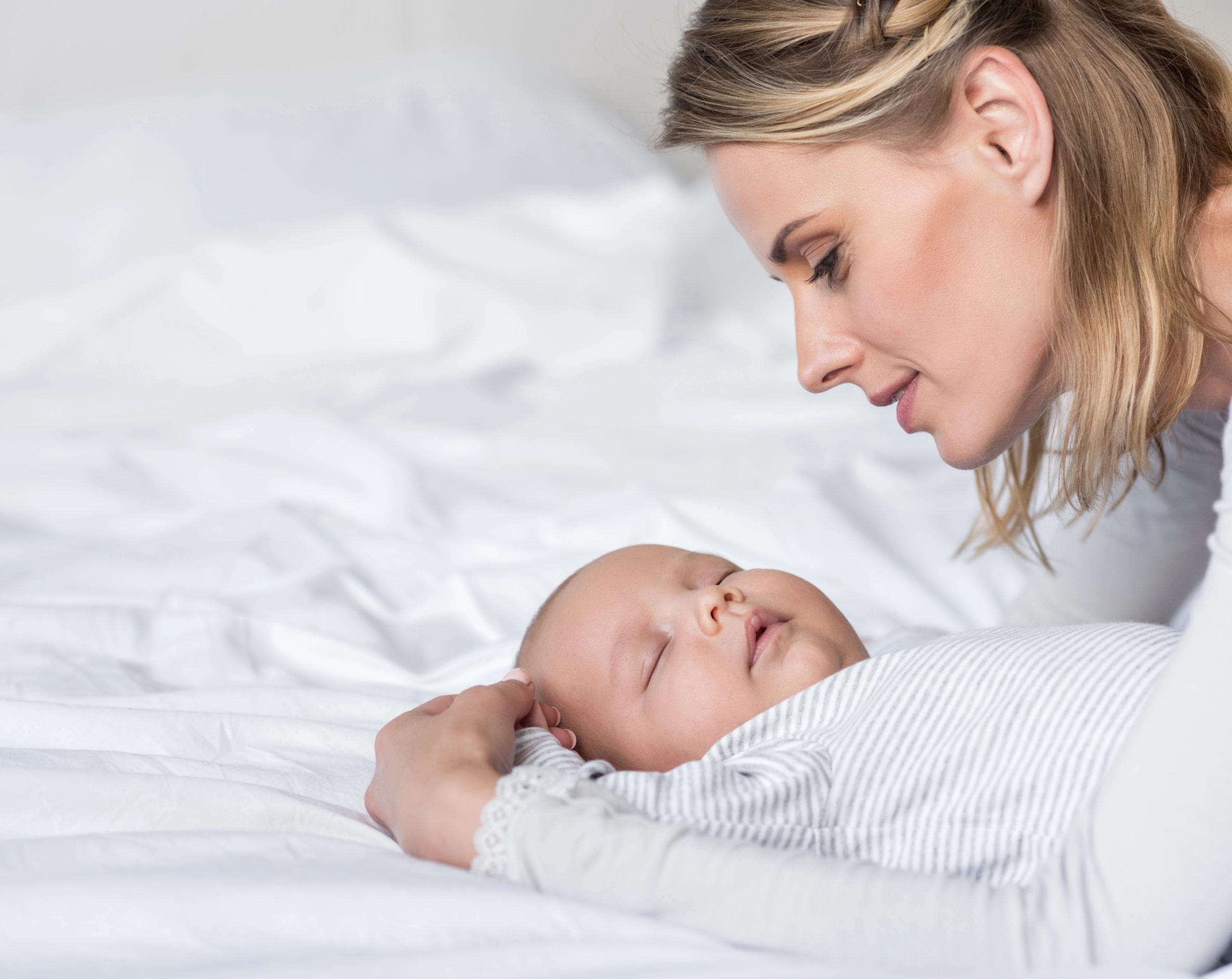 Mamá sostiene a su bebé recostado en una cama antes de realizar la limpieza del cordón umbilical.