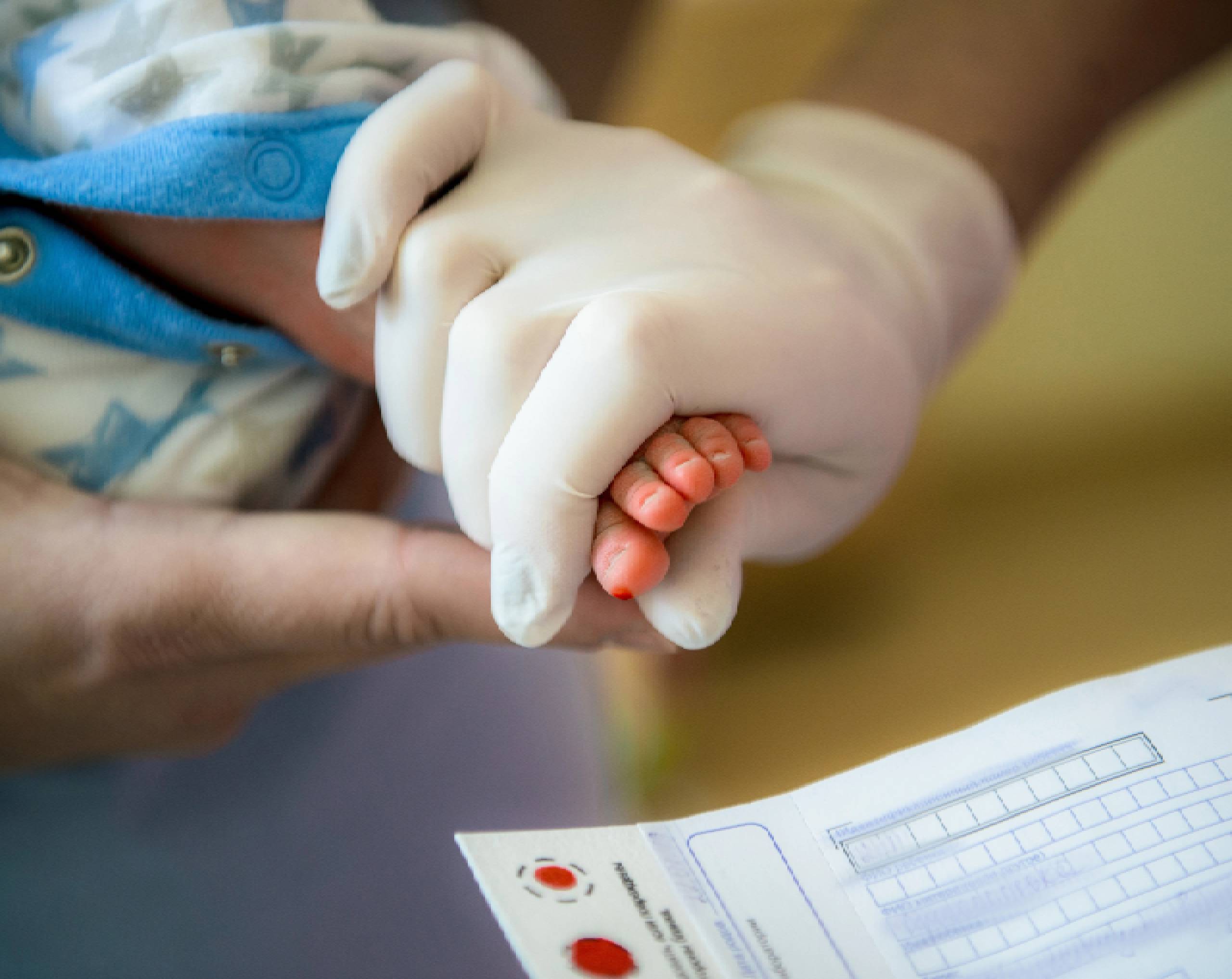 Enfermera haciéndole tamiz neonatal a bebé recién nacido tomando muestras de sangre