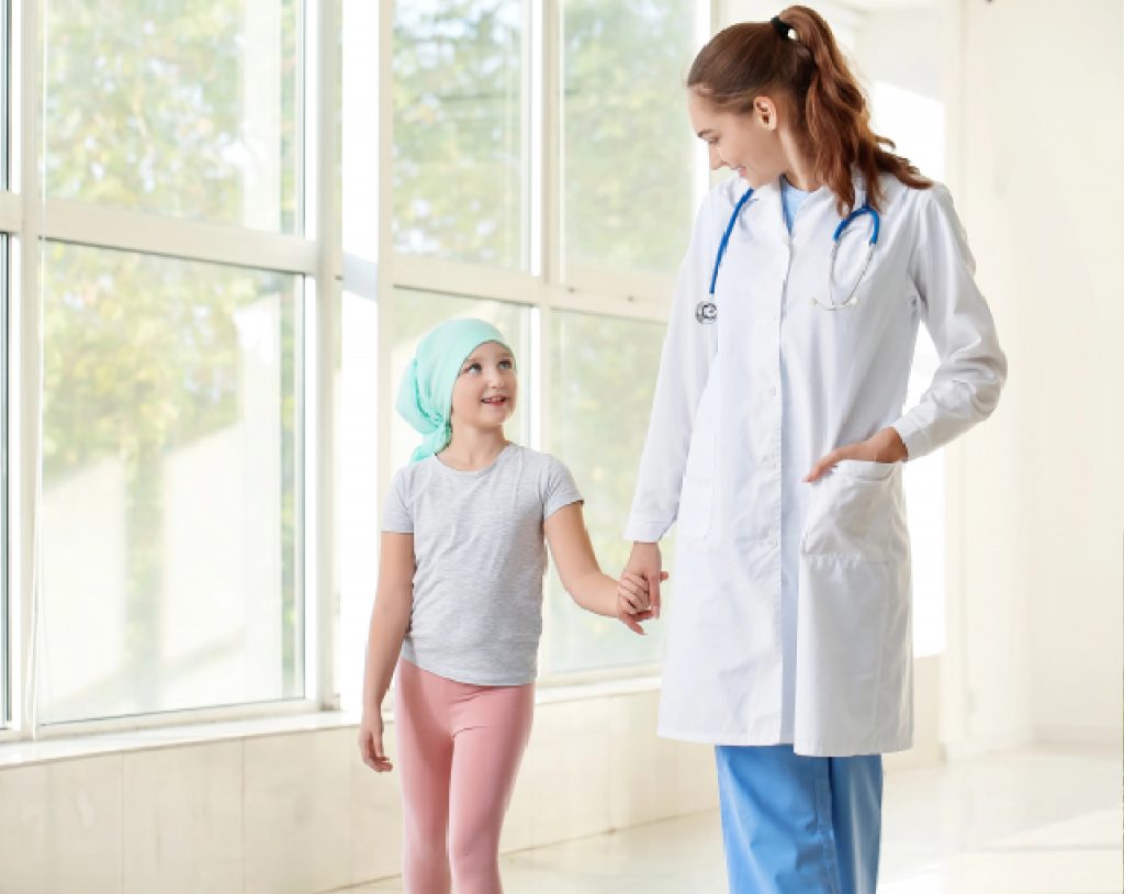 Médico especialista en oncología pediátrica acompaña a caminar a una paciente de cáncer infantil.