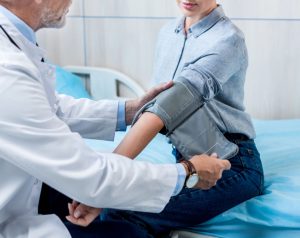 Médico revisando la presión arterial a paciente antes del diagnóstico.