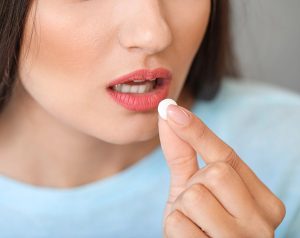 Mujer de mediana edad tomando una pastilla como parte del tratamiento médico para la tuberculosis.