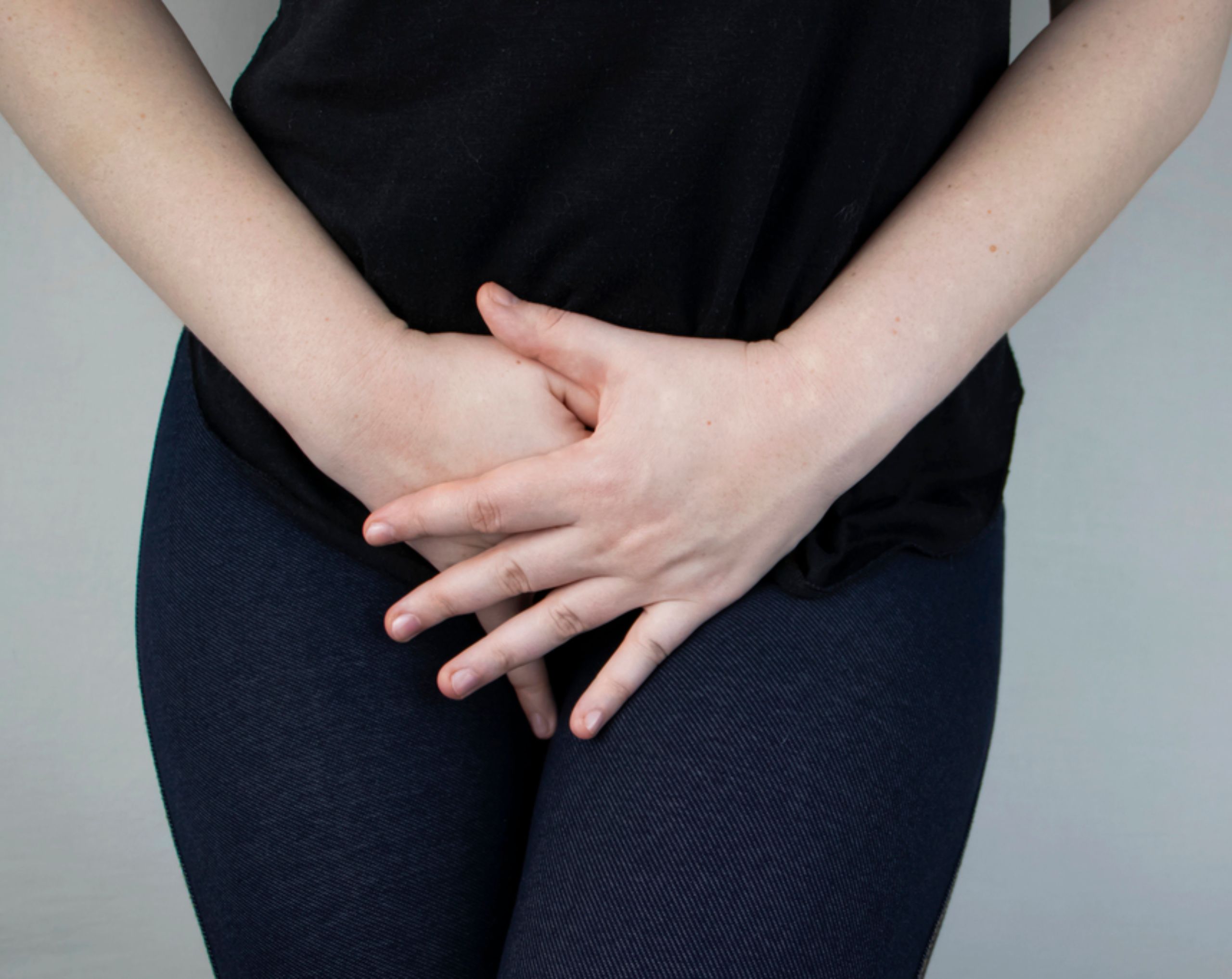 Mujer sostiene la zona genital con ambas manos debido a picazón, uno de los posibles síntomas de la clamidia.
