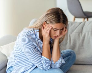 Mujer de mediana edad sentada en el suelo de su habitación tras experimentar mareos, asociados a la septicemia.