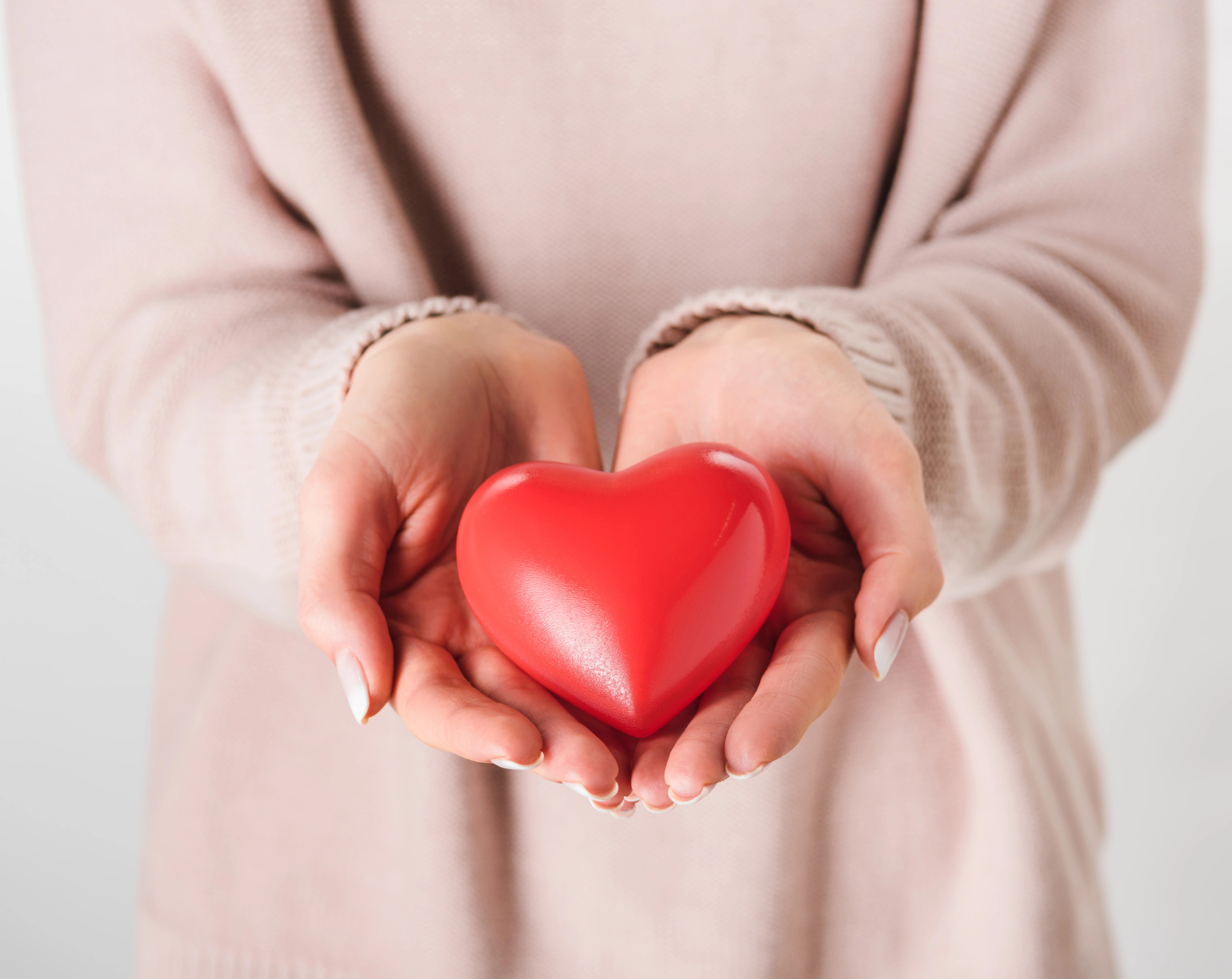 Mujer sosteniendo un corazón rojo de plástico entre sus manos
