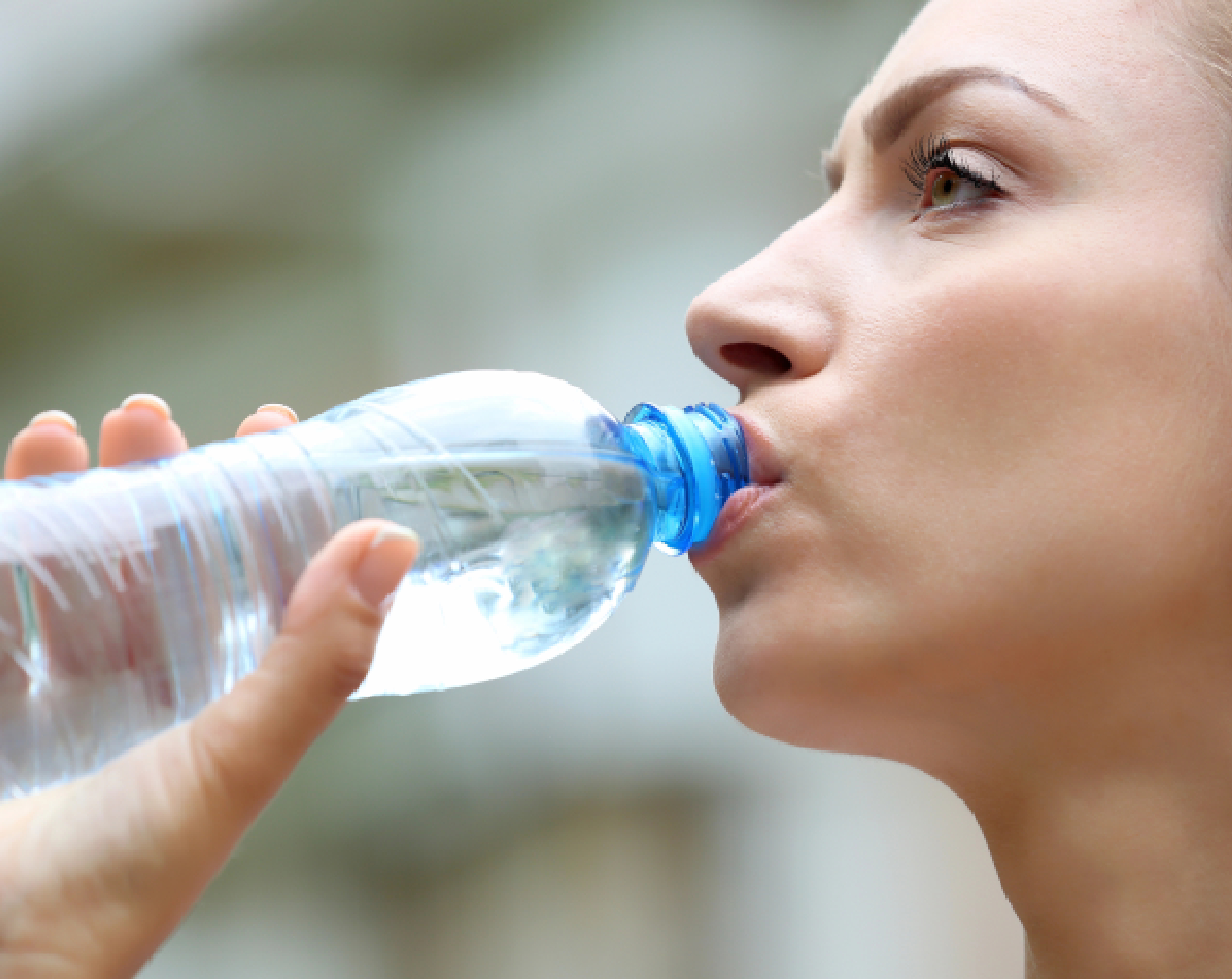 Mujer con deshidratación leve bebe agua de una botella de plástico.