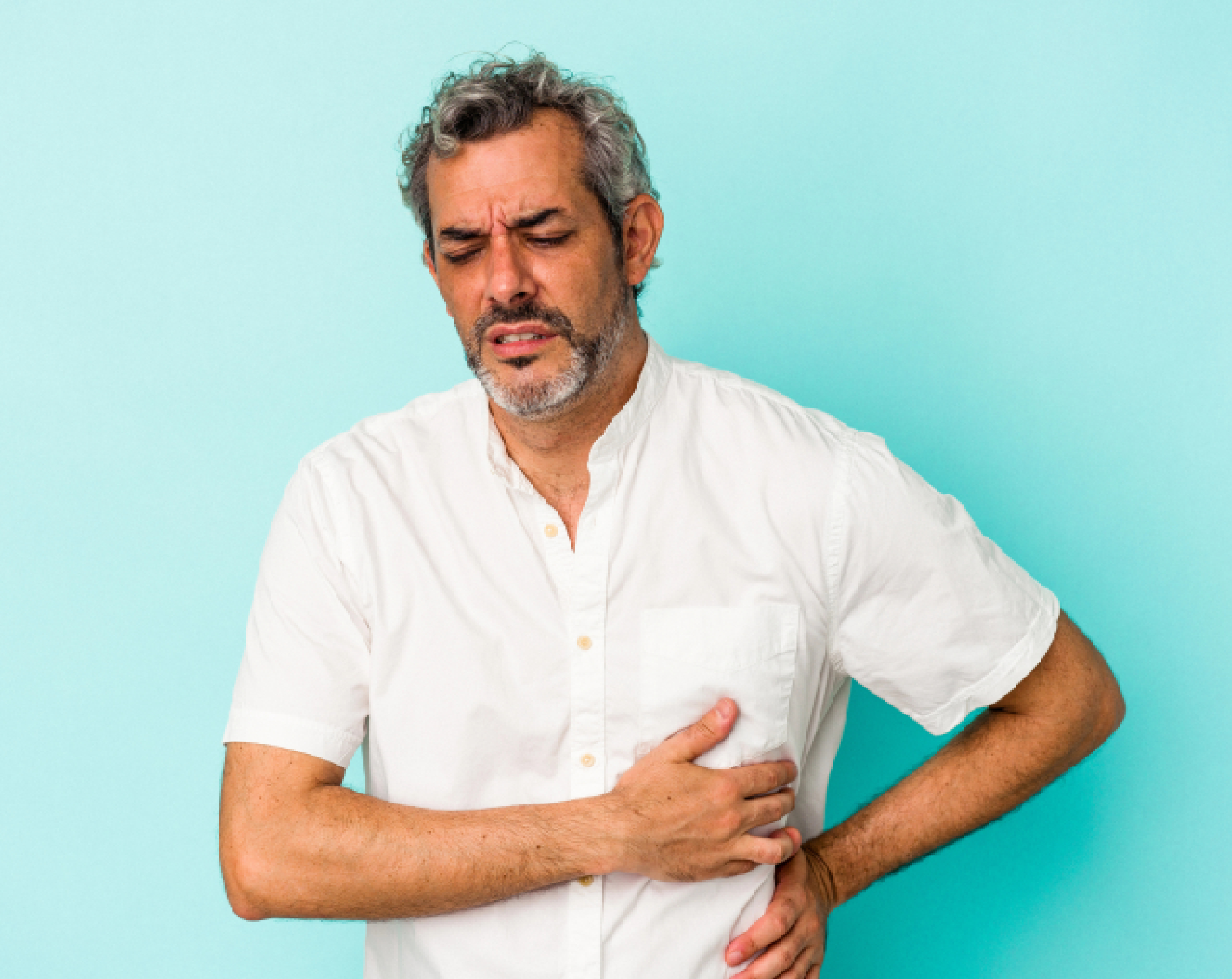 Hombre de edad media tocándose el abdomen por dolor relacionado a hígado graso o esteatosis hepática.