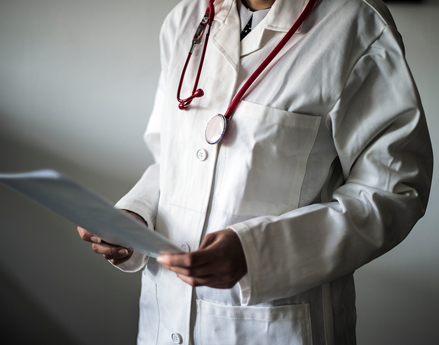 Médico sosteniendo una hoja, con un estetoscopio colgando de su cuello.